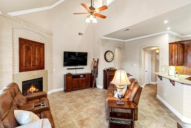 living room with ornamental molding, a tile fireplace, and ceiling fan