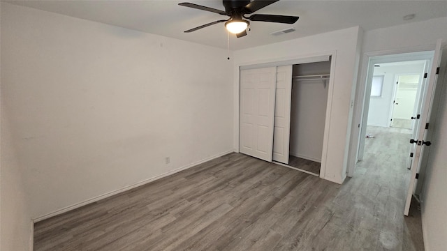 unfurnished bedroom featuring ceiling fan, a closet, and light hardwood / wood-style flooring