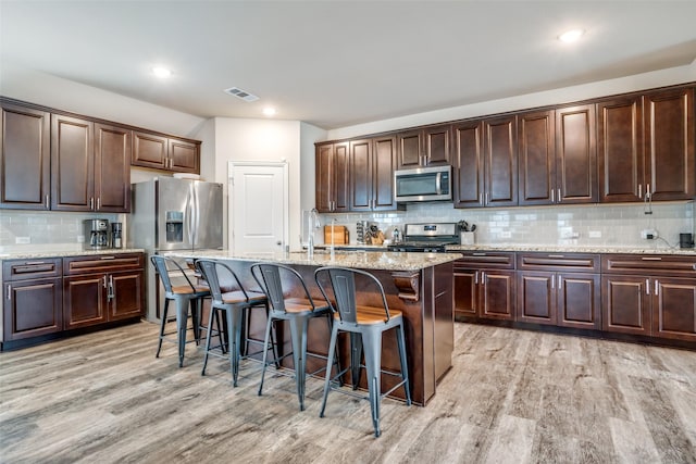 kitchen featuring dark brown cabinetry, sink, an island with sink, and appliances with stainless steel finishes