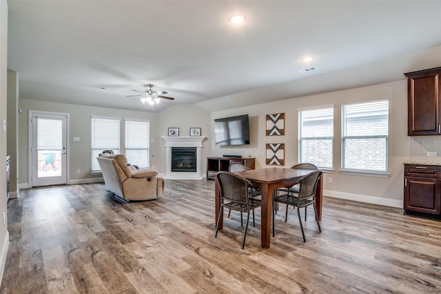 dining area featuring lofted ceiling, ceiling fan, wood-type flooring, and a healthy amount of sunlight