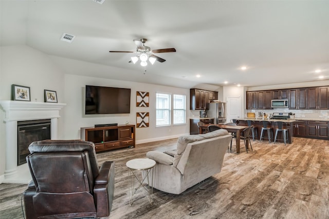 living room featuring lofted ceiling, hardwood / wood-style floors, and ceiling fan