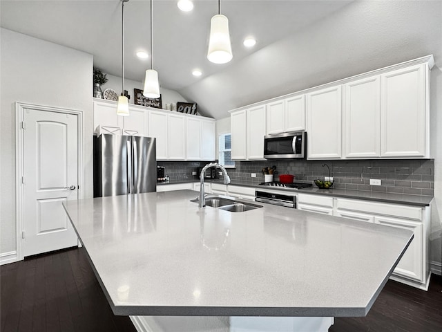 kitchen with appliances with stainless steel finishes, pendant lighting, lofted ceiling, sink, and a large island