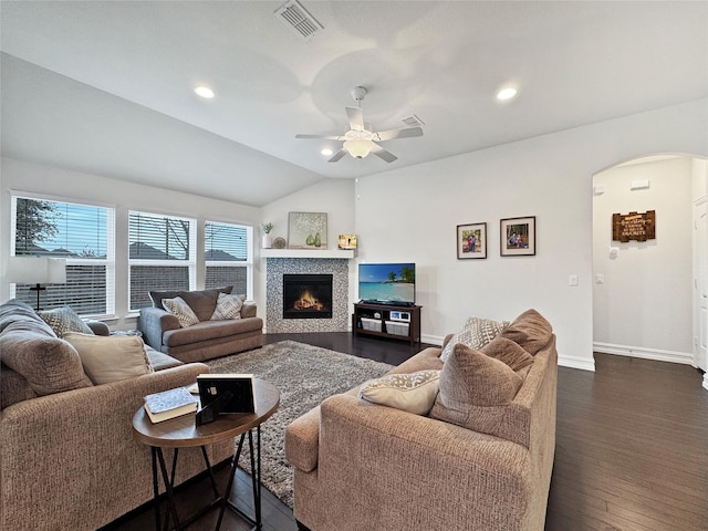 living room featuring ceiling fan, lofted ceiling, dark hardwood / wood-style flooring, and a tiled fireplace