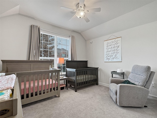 carpeted bedroom featuring a nursery area, ceiling fan, and lofted ceiling