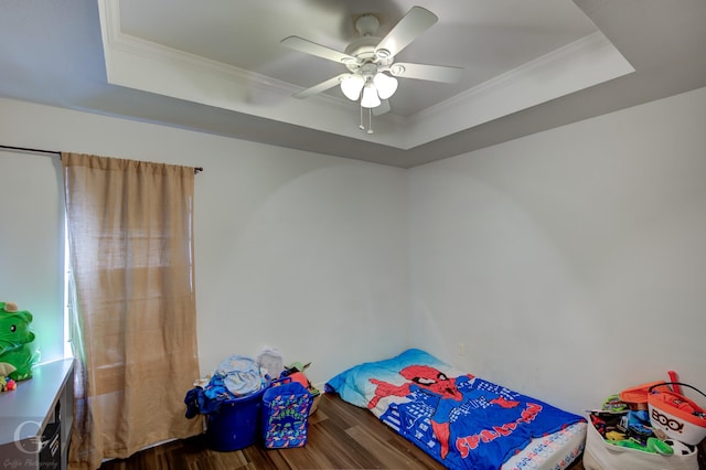 bedroom with ornamental molding, hardwood / wood-style floors, ceiling fan, and a tray ceiling