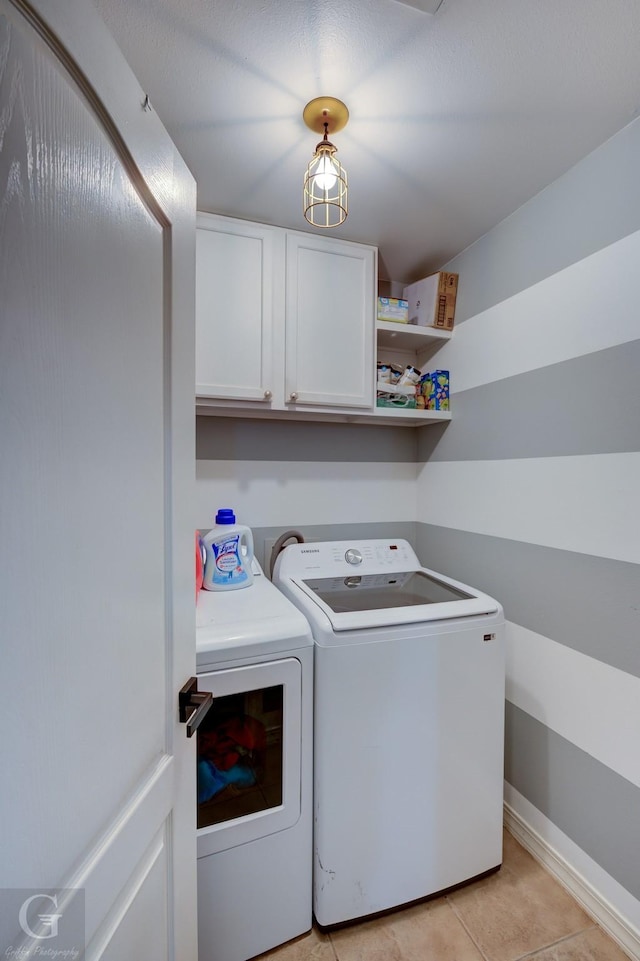 laundry room with light tile patterned floors, washing machine and dryer, and cabinets