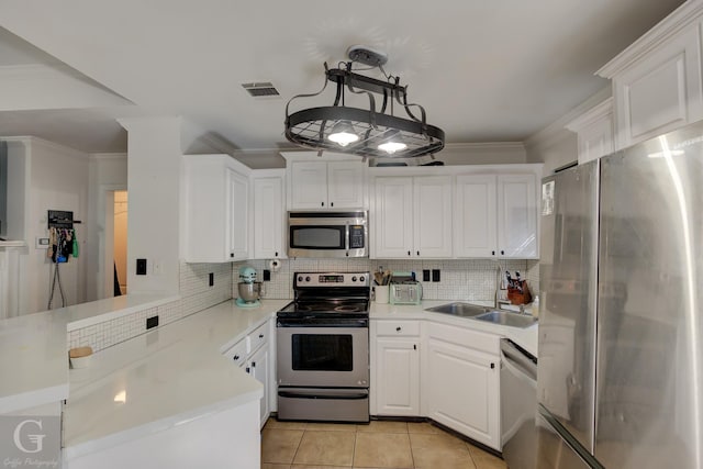 kitchen featuring white cabinetry, appliances with stainless steel finishes, kitchen peninsula, and decorative light fixtures