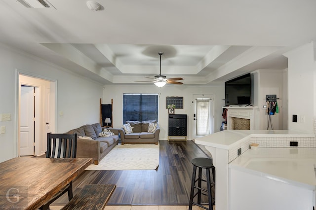 living room featuring a raised ceiling, crown molding, ceiling fan, and dark hardwood / wood-style flooring