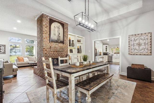 dining area with a textured ceiling, an inviting chandelier, dark tile patterned flooring, and a fireplace