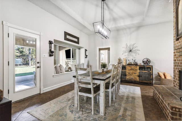 dining room with a fireplace, a raised ceiling, and dark tile patterned floors