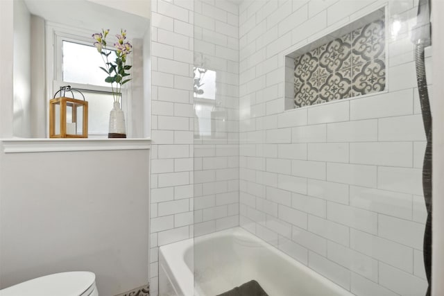 bathroom featuring tiled shower / bath and toilet