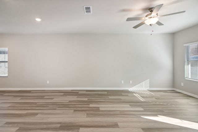 empty room featuring ceiling fan, plenty of natural light, and light wood-type flooring