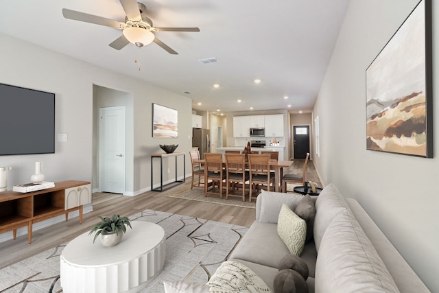 living room featuring light hardwood / wood-style flooring and ceiling fan