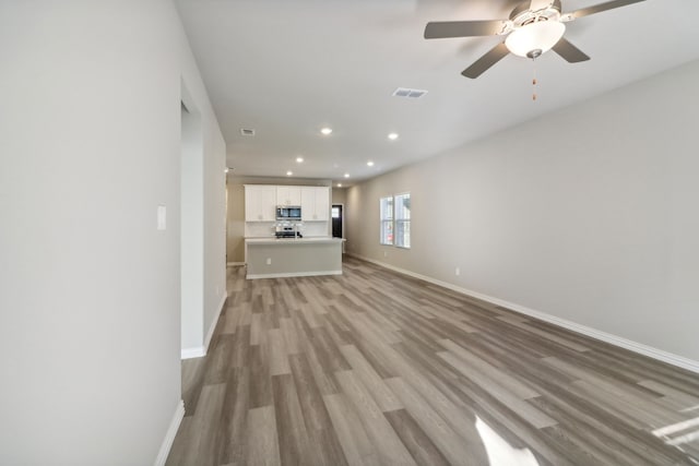 unfurnished living room with ceiling fan and light wood-type flooring