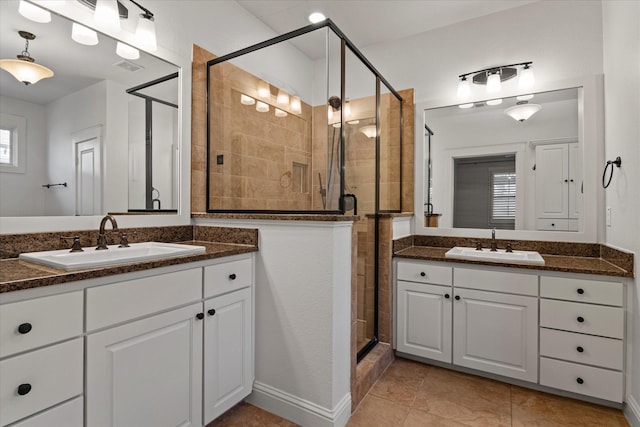 bathroom featuring vanity, tile patterned flooring, a shower with shower door, and a wealth of natural light