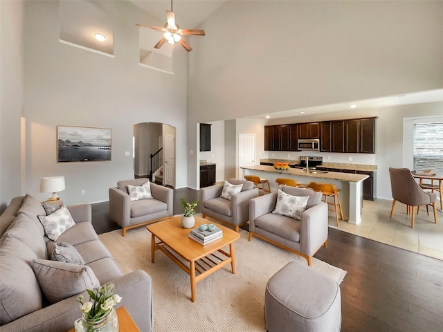 living room featuring a towering ceiling, ceiling fan, and light hardwood / wood-style flooring