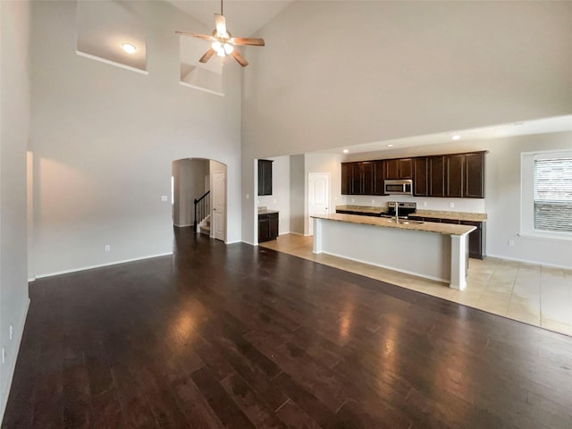 unfurnished living room with high vaulted ceiling, sink, ceiling fan, and light hardwood / wood-style flooring