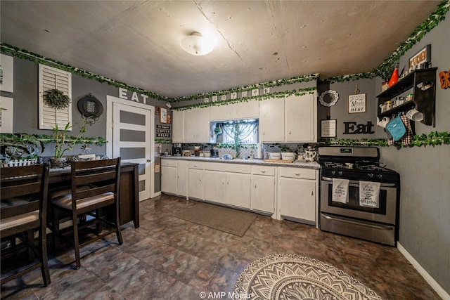 kitchen featuring stainless steel gas stove, tasteful backsplash, and white cabinets