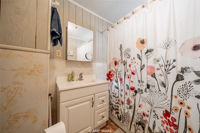 bathroom featuring vanity, wooden walls, a textured ceiling, and walk in shower