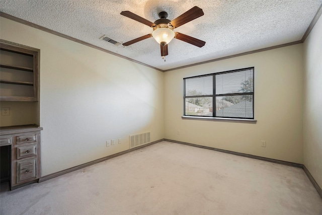 carpeted spare room featuring crown molding, ceiling fan, and a textured ceiling