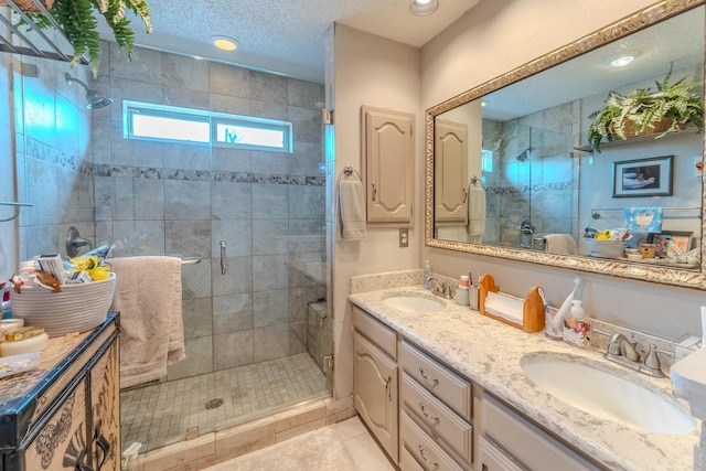 bathroom featuring vanity, a shower with door, tile patterned floors, and a textured ceiling