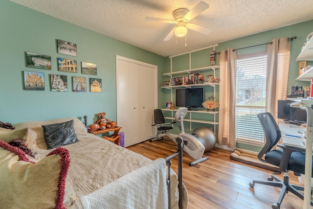 bedroom featuring a textured ceiling, light hardwood / wood-style floors, a closet, and ceiling fan