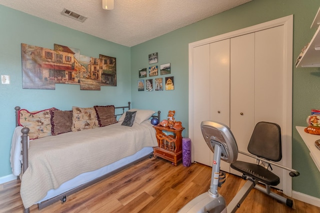 bedroom with ceiling fan, a textured ceiling, a closet, and light wood-type flooring