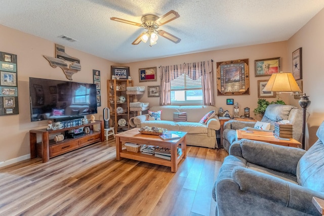 living room with ceiling fan, light hardwood / wood-style floors, and a textured ceiling