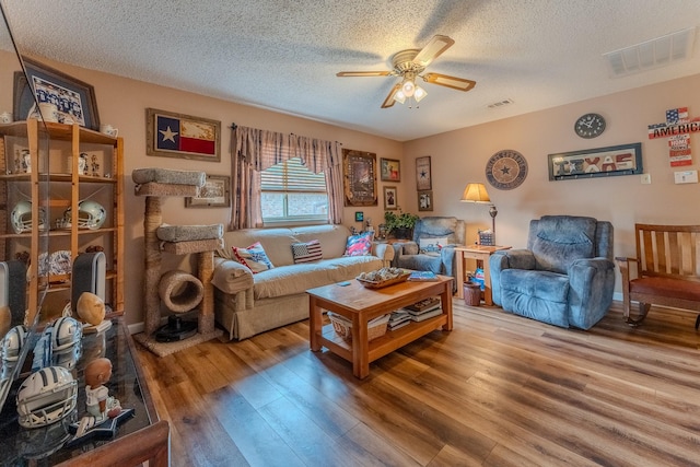 living room featuring hardwood / wood-style flooring, ceiling fan, and a textured ceiling