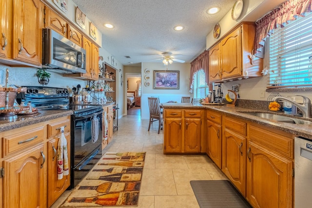 kitchen with light tile patterned flooring, sink, a textured ceiling, ceiling fan, and stainless steel appliances