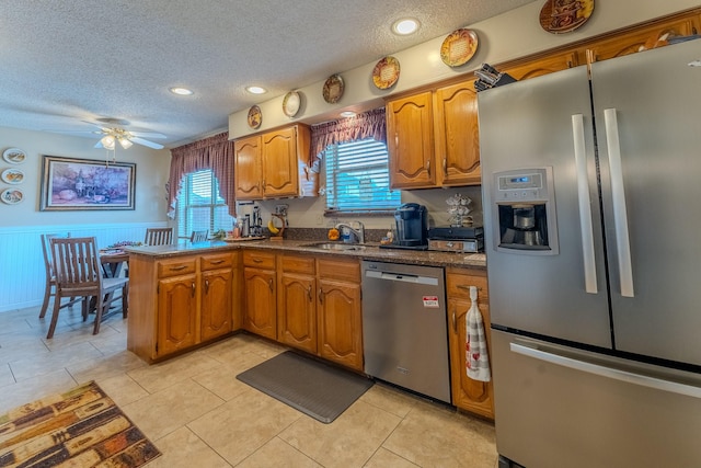 kitchen with light tile patterned flooring, sink, kitchen peninsula, stainless steel appliances, and a textured ceiling