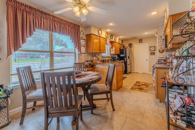 tiled dining room with ceiling fan, a wealth of natural light, and a textured ceiling