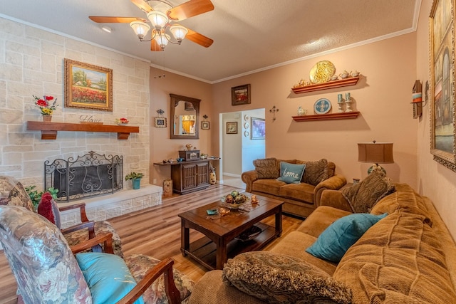 living room with crown molding, a textured ceiling, ceiling fan, a fireplace, and hardwood / wood-style floors