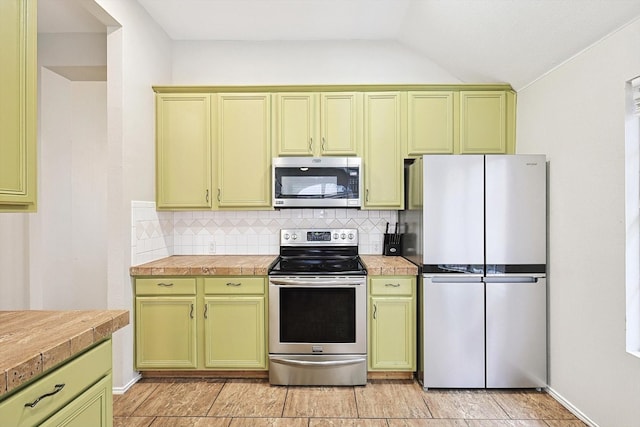 kitchen with stainless steel appliances, tasteful backsplash, vaulted ceiling, and green cabinets