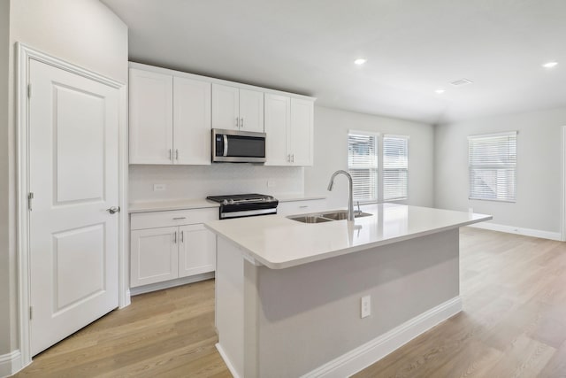 kitchen featuring an island with sink, appliances with stainless steel finishes, sink, and white cabinets