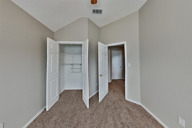 unfurnished bedroom with lofted ceiling, ceiling fan, a textured ceiling, light carpet, and a closet