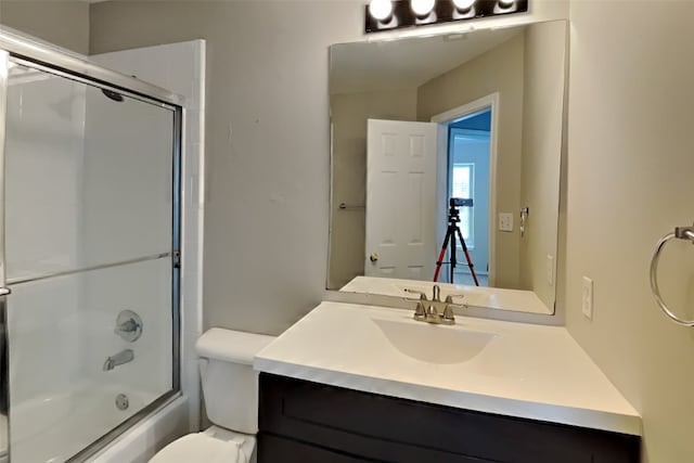 full bathroom featuring vanity, bath / shower combo with glass door, and toilet