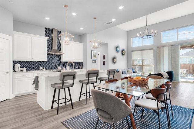 dining area featuring sink, a chandelier, a high ceiling, and light wood-type flooring