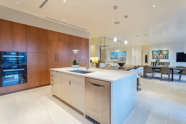 kitchen featuring sink, decorative light fixtures, dishwasher, an island with sink, and white cabinets