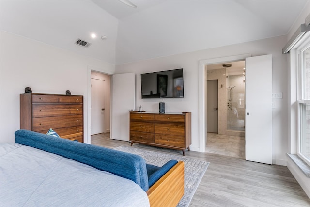 bedroom featuring ensuite bath, vaulted ceiling, multiple windows, and light hardwood / wood-style flooring