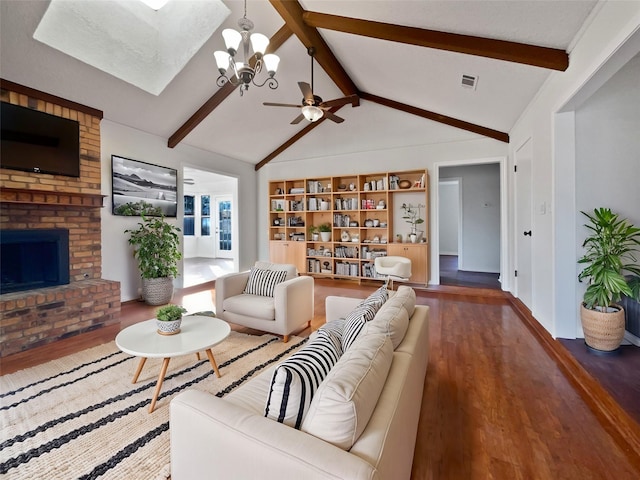 living room with ceiling fan with notable chandelier, dark hardwood / wood-style flooring, lofted ceiling with beams, and a brick fireplace