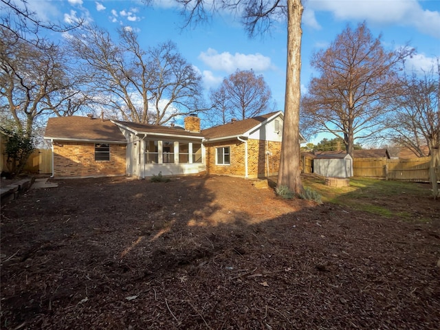 rear view of property with a sunroom and a shed