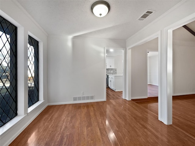 interior space featuring crown molding, wood-type flooring, and a textured ceiling