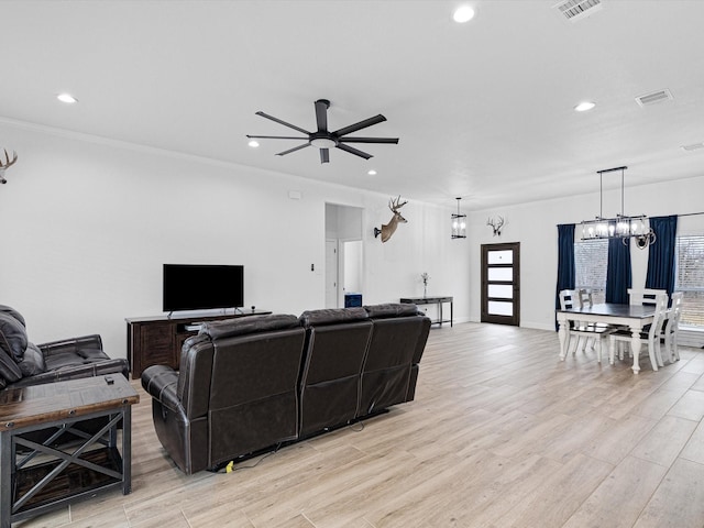 living room featuring ceiling fan with notable chandelier and light hardwood / wood-style flooring