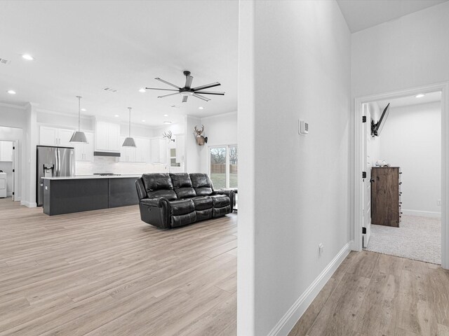 living room with crown molding, light hardwood / wood-style floors, and ceiling fan