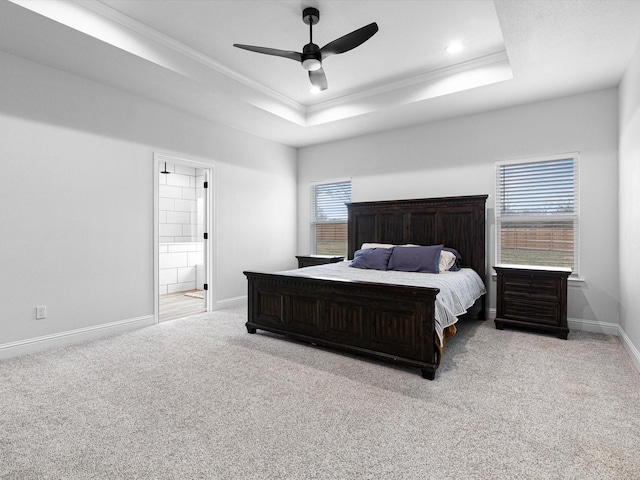 bedroom with light carpet, a tray ceiling, multiple windows, and ceiling fan