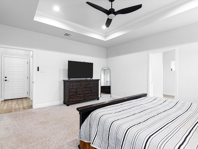 carpeted bedroom with crown molding, ceiling fan, and a raised ceiling