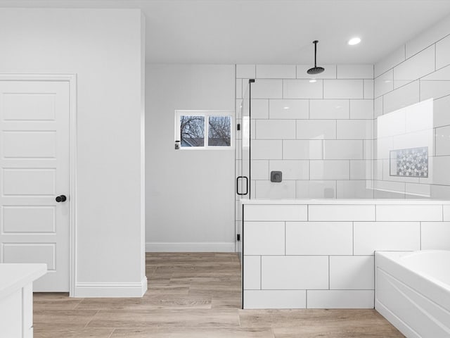 bathroom with wood-type flooring, separate shower and tub, and vanity