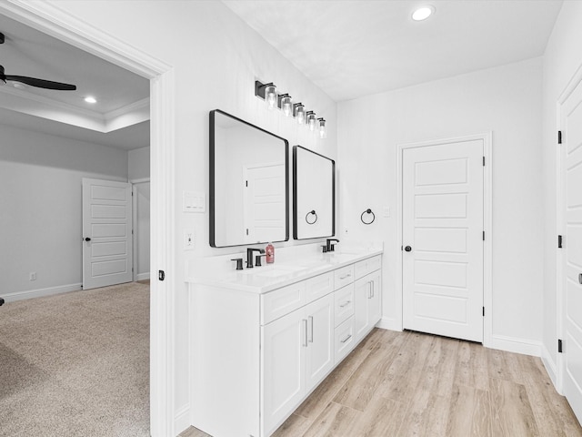 bathroom with vanity, hardwood / wood-style floors, a tray ceiling, and ceiling fan