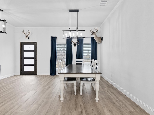 unfurnished dining area with crown molding, a chandelier, and light wood-type flooring